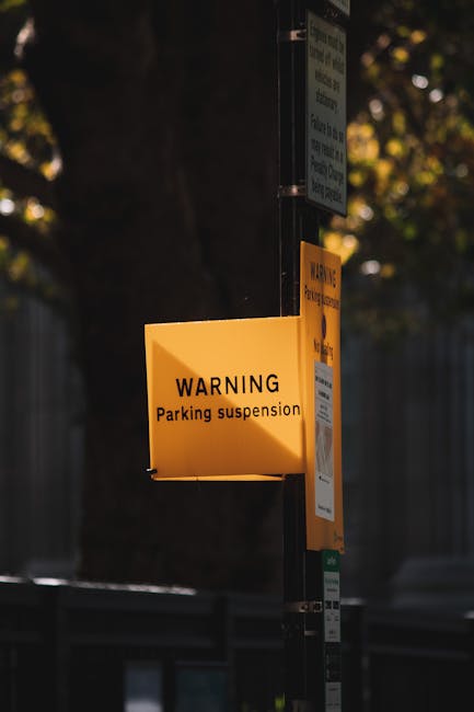 Close-up of a round, red-bordered 'No Parking' sign with a bold black 'P' crossed out in red, mounted on a vibrant wall painted with large patches of orange, pink, and purple. The sign is positioned o